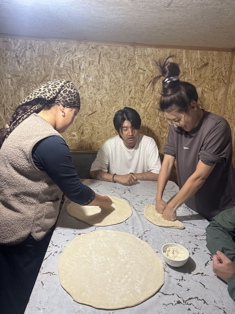 Guests rolling out bread dough together with the family