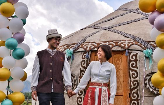 Bek and Ruby in traditional clothes in front of a decorated yurt