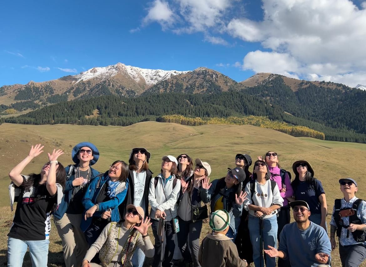 Our group waving in an autumn meadow below snowy peaks