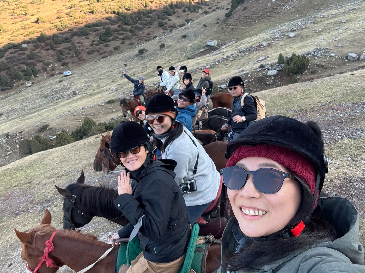 Guests smiling on horseback on a mountain trail