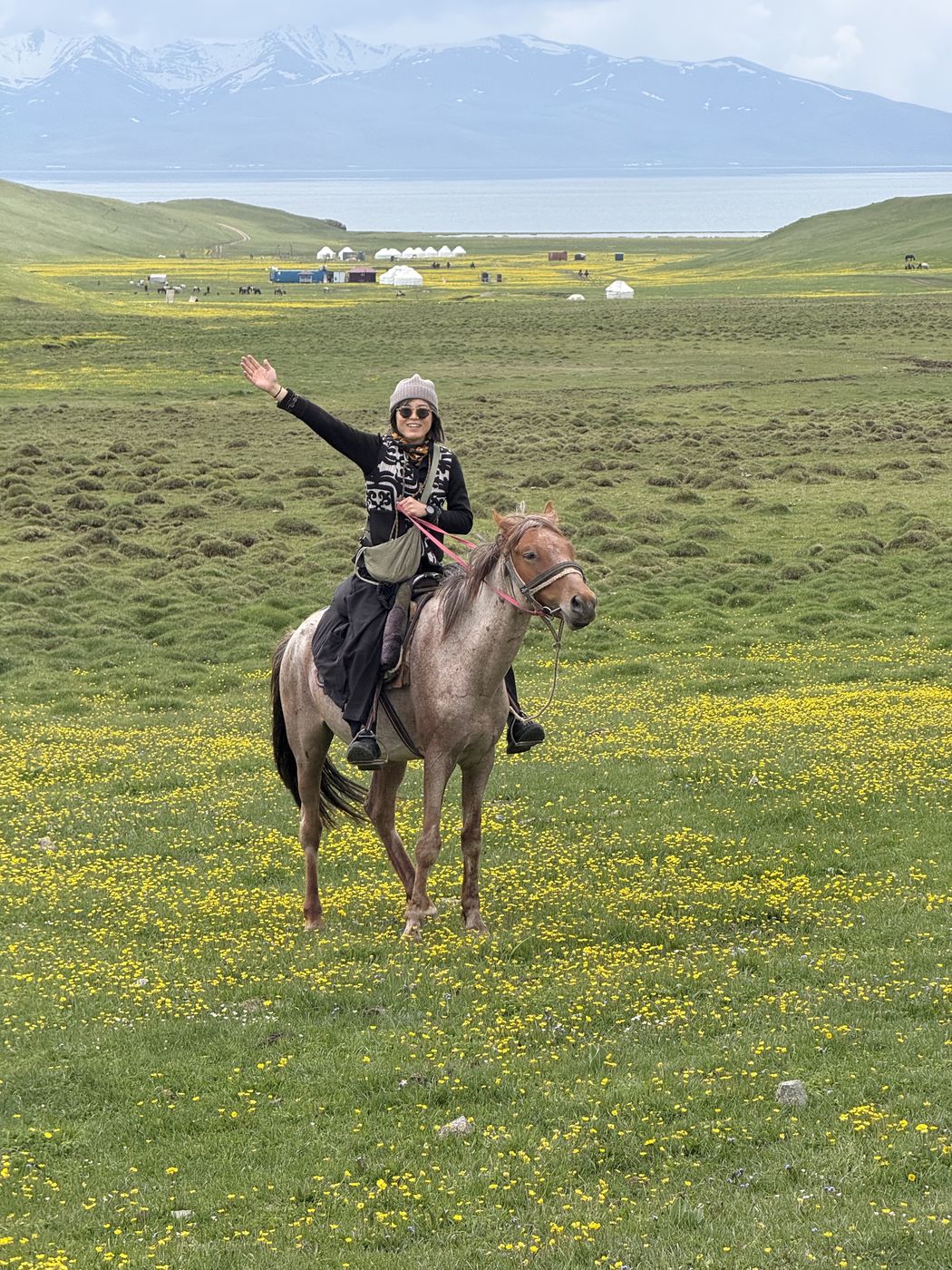 A guest waving from horseback on the summer pasture