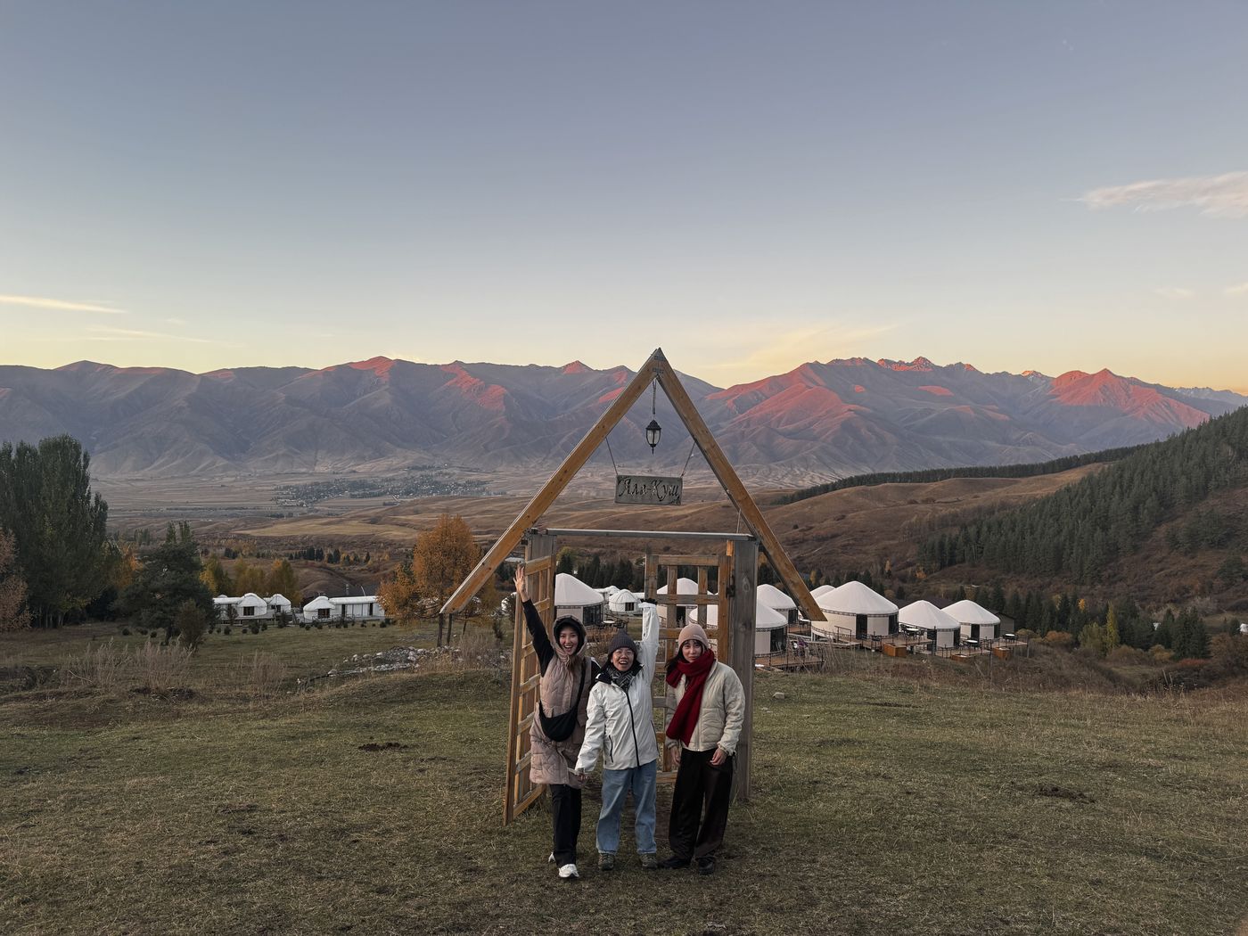 Guests at a wooden arch by the yurts at sunset