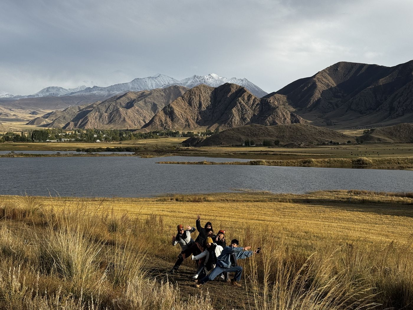 Guests posing in golden grass by a mountain lake
