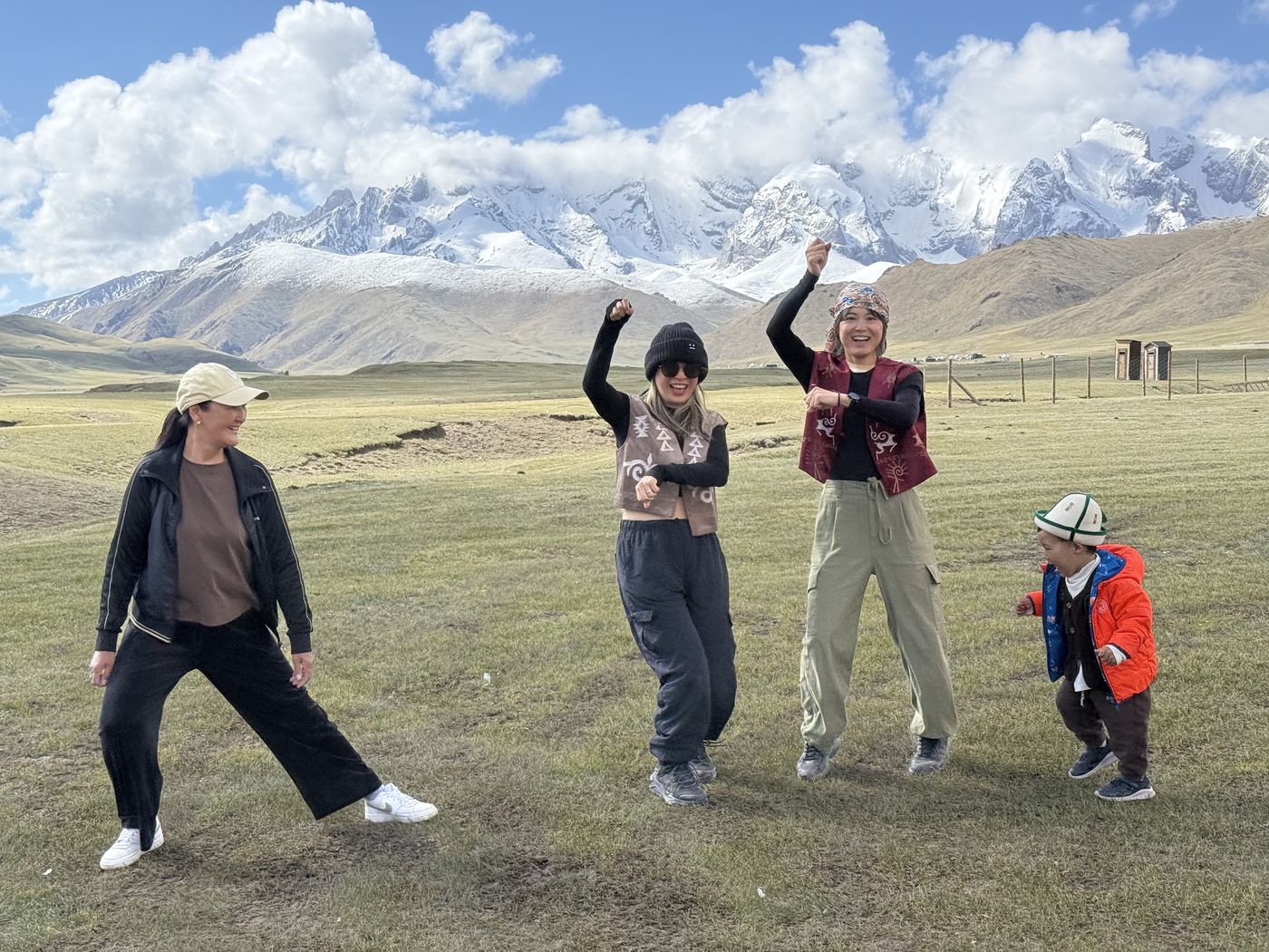 Guests dancing on the steppe below snowy mountains