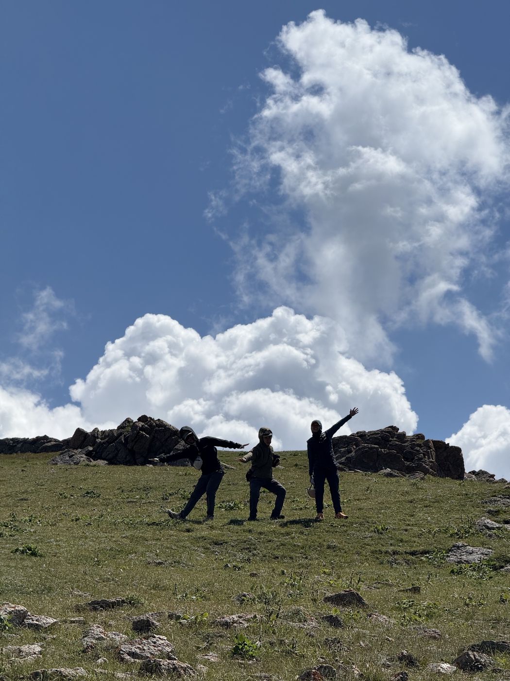 Guests posing on a hilltop under big clouds