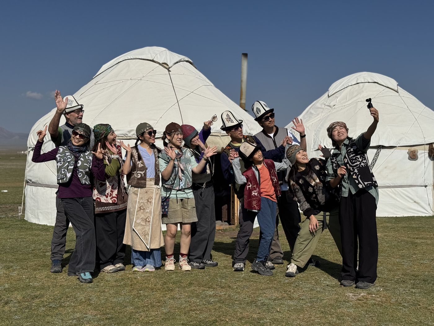 Guests in Kyrgyz vests and hats by the yurts